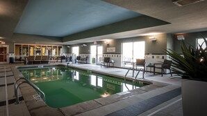 Une piscine intérieure avec un sol carrelé, un poste de surveillance pour sauveteur et un panneau indiquant l’absence de sauveteur.