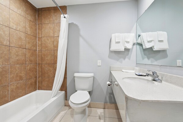 A bathroom with a bathtub, toilet, sink, and a mirror.