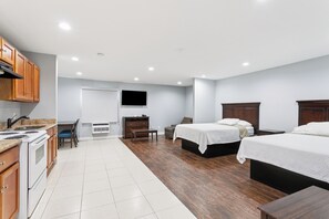 A modern hotel room with a kitchen area, two beds, a flat-screen TV, and a dining table. - LaPlace Motel (LaPlace)