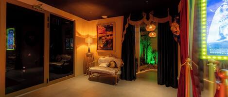 A room with a red carpet, a sofa, a lamp, a poster, and a green-lit area.