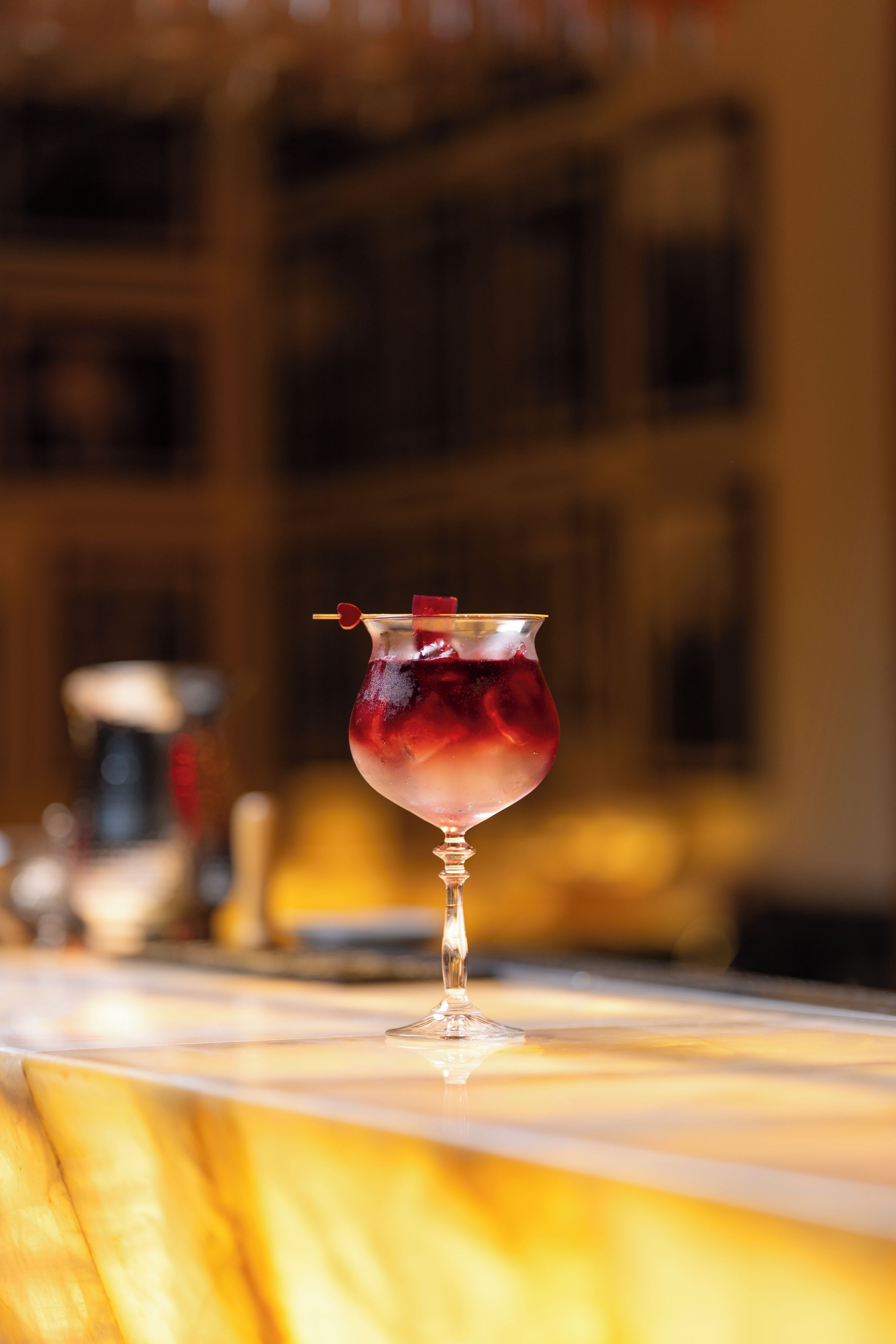 Ein Cocktailglas mit herzförmiger Dekoration auf einer Bar.