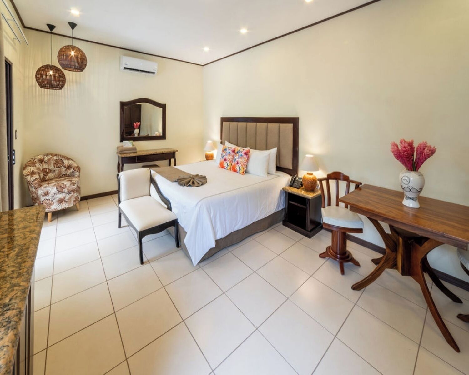 Habitación de hotel con cama, mesita de noche, silla, escritorio y mesa de comedor.