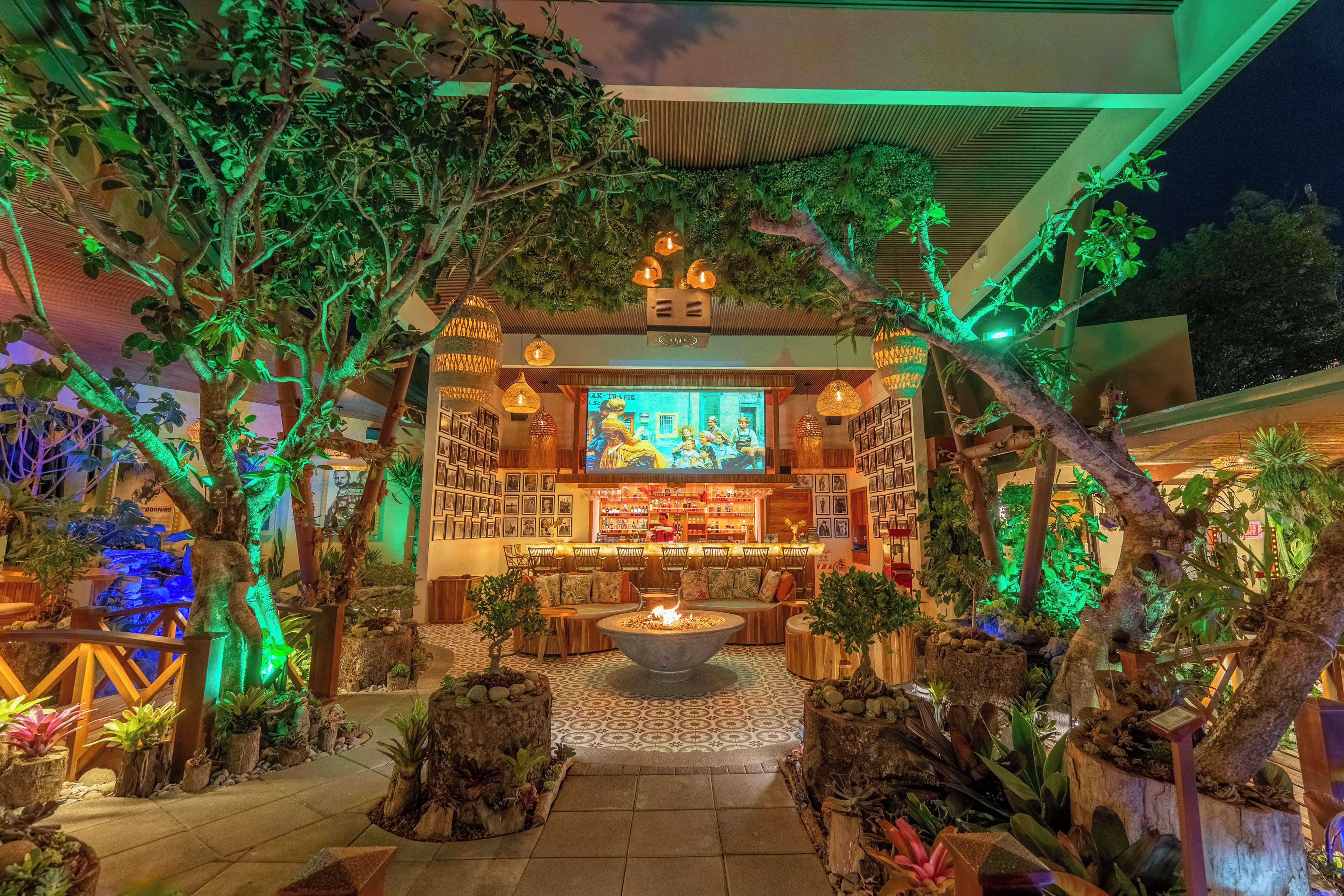 Ein Wintergarten mit Barbereich, Sitzgelegenheiten und einem Kamin.