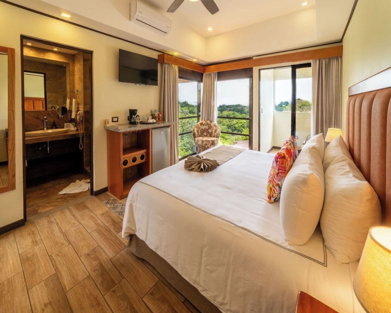Une chambre d’hôtel avec un lit, un bureau et une chaise, une télévision et un balcon avec vue.
