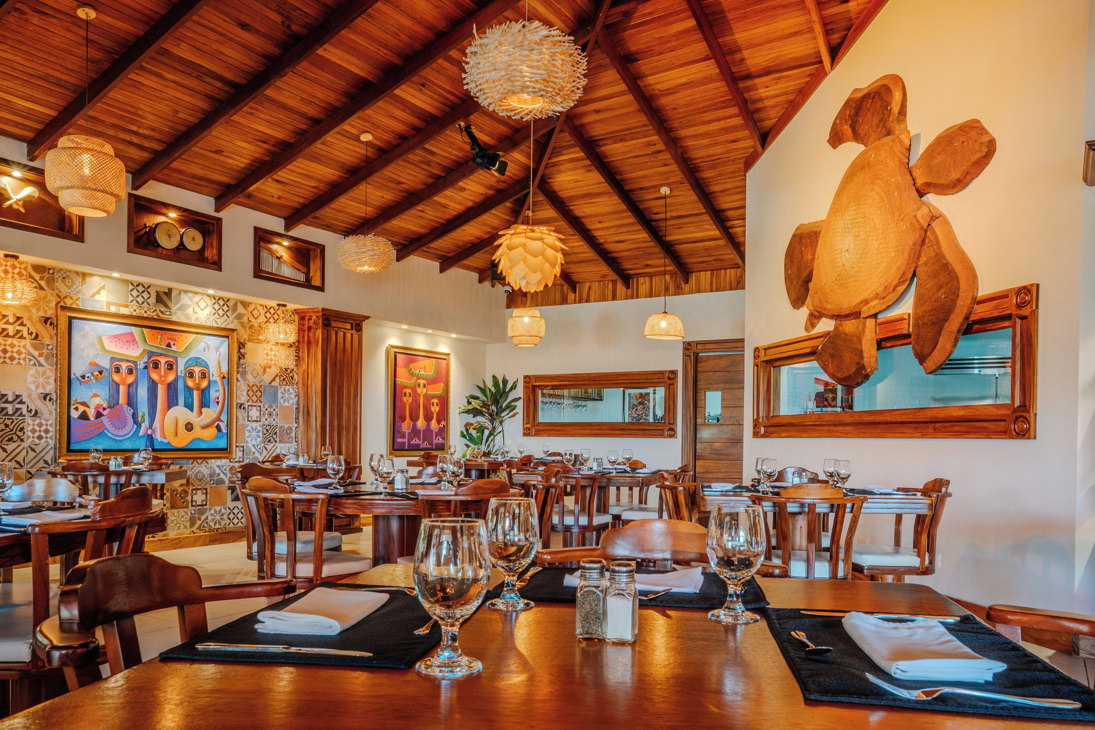 A restaurant with wooden tables, chairs, and a large turtle sculpture on the wall.