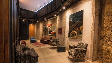 A modern interior with a sofa set, patterned chairs, and a large painting on the wall.