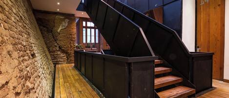 A staircase with a wooden finish, a stone wall, and a wooden door with the number 14.