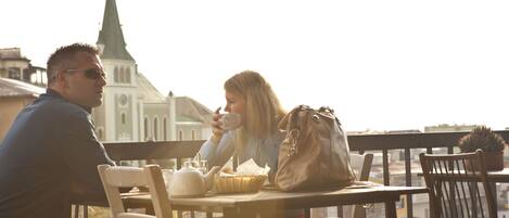 Two people sitting at a table with a view of a building with a spire in the background.