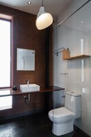 A modern bathroom with a large mirror, a white sink, a toilet, and a glass shower enclosure.