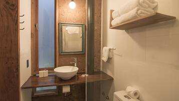 A bathroom with a wooden vanity, a white sink, a mirror, a towel rack, and a toilet.