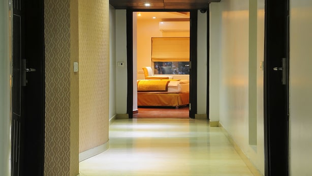 A hotel hallway with a bed in the background. - Trimrooms Palm D'or (New Delhi)