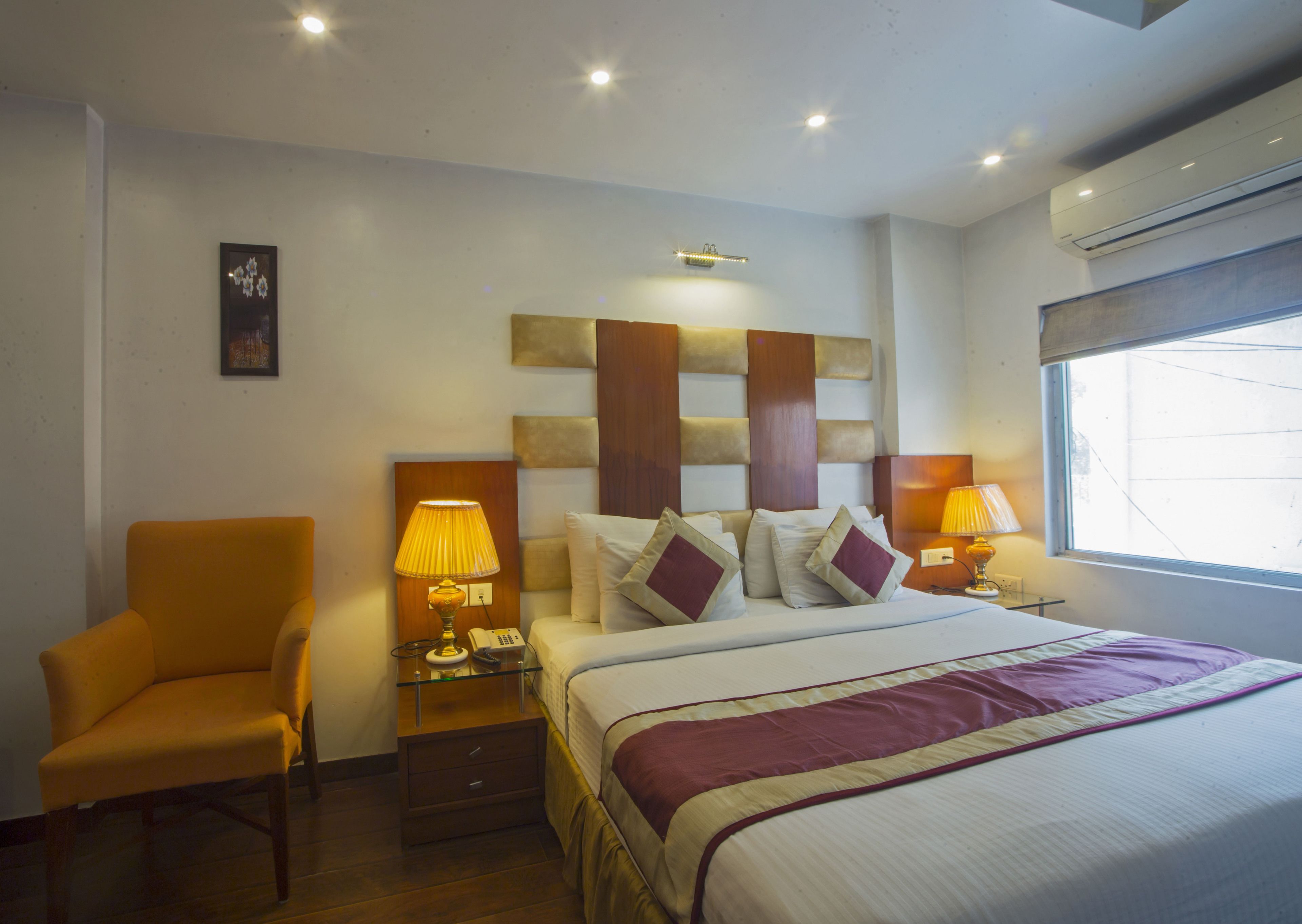 A hotel room with a bed, bedside tables, a chair, and a window.