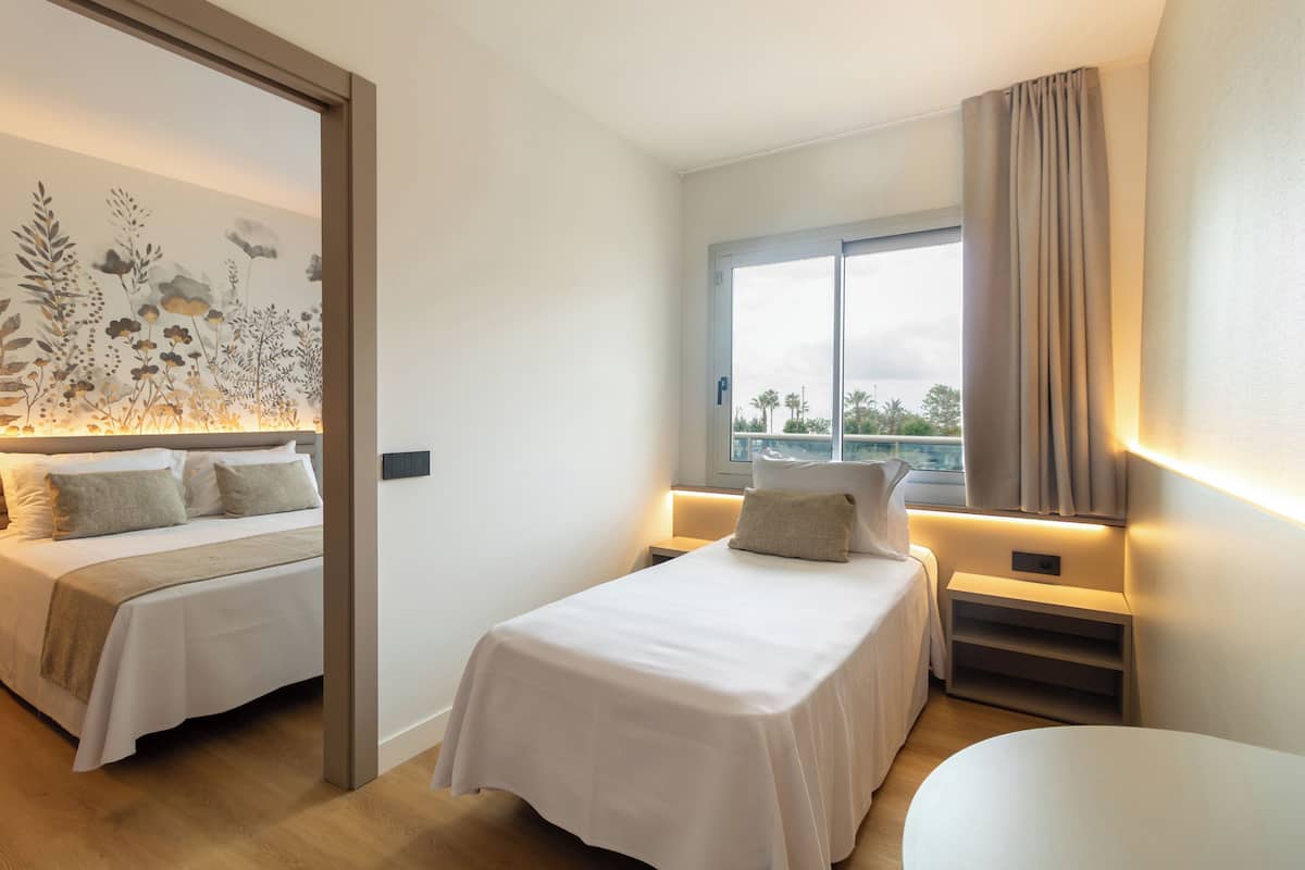Une chambre d’hôtel moderne avec deux lits, une grande fenêtre offrant une belle vue et une œuvre d’art accrochée au mur.