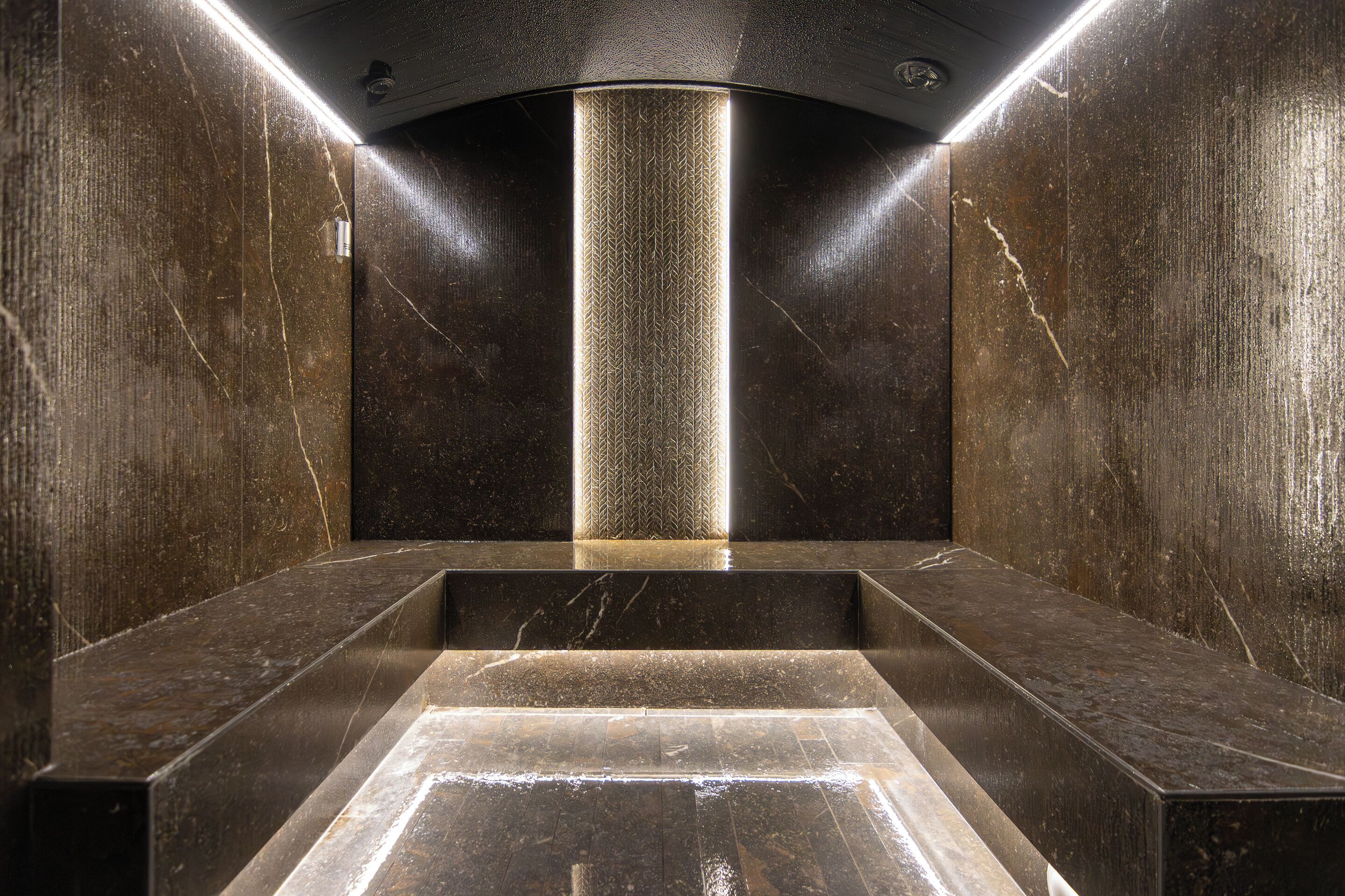 A modern elevator interior with a central light column and marble steps.