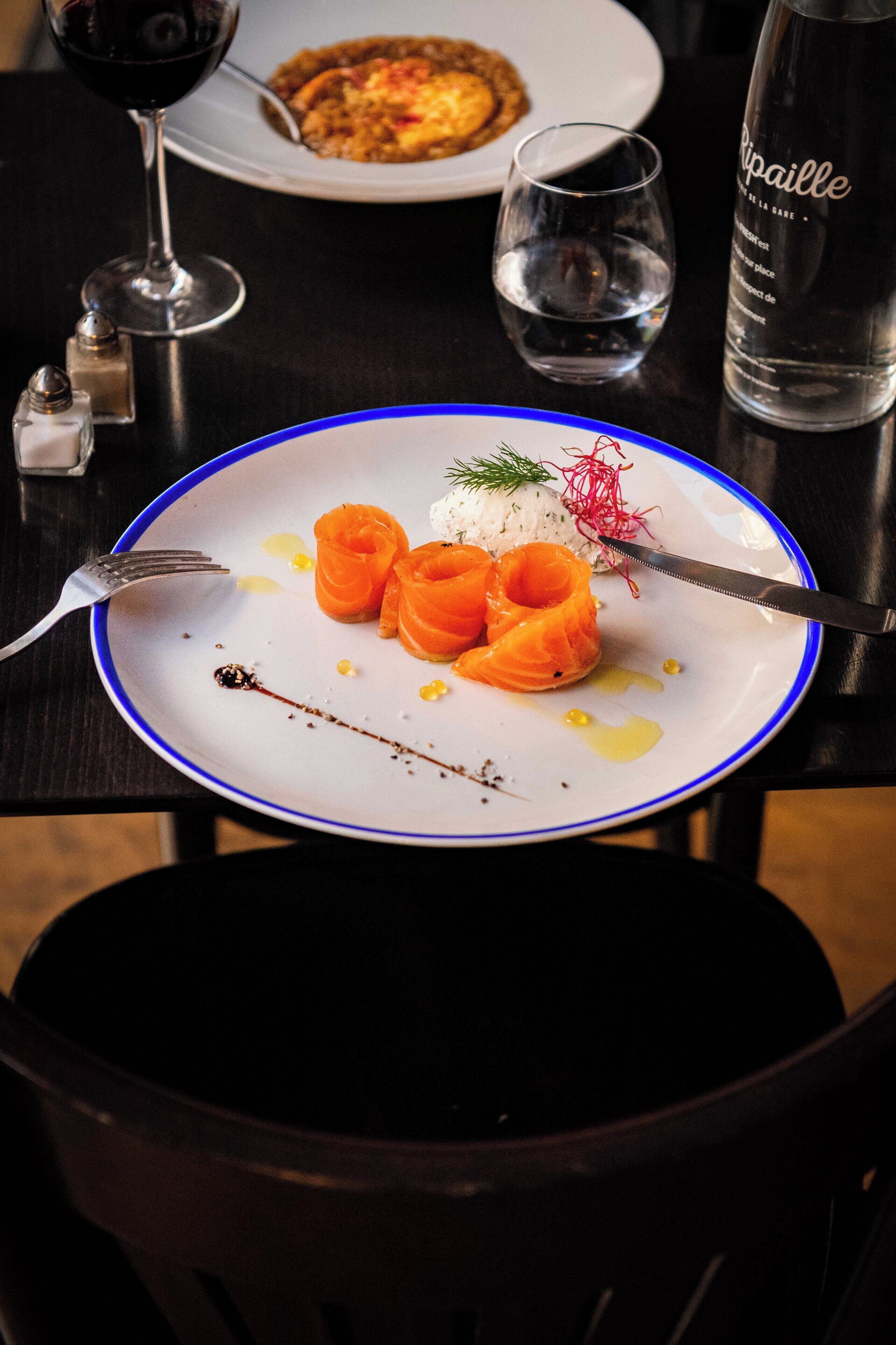 Une table à manger avec une assiette de nourriture, un verre à vin et une bouteille d’eau.
