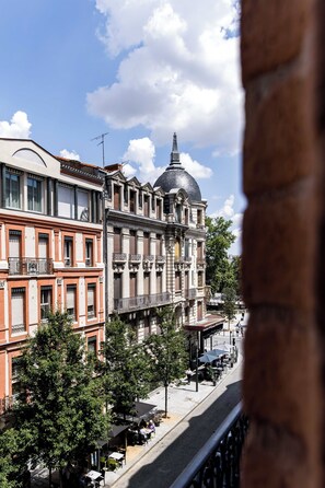 Blick auf eine Straße mit Gebäuden, darunter ein markantes Gebäude mit Kuppel und roter Fassade.