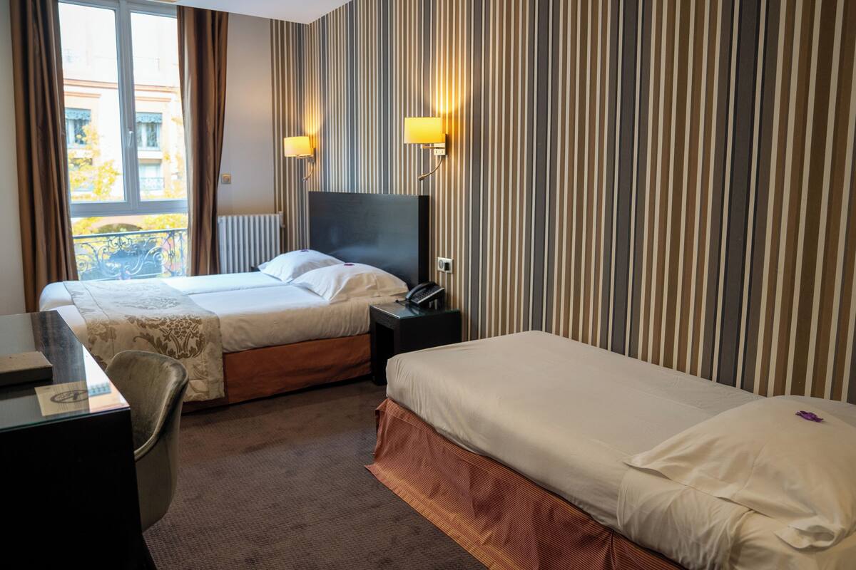 Een hotelkamer met twee bedden, een bureau en een stoel.