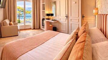 Quarto de hotel com uma cama grande, uma escrivaninha, uma cadeira, televisão e varanda com vista.