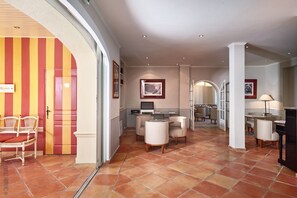 A spacious lobby with a dining area, a reception desk, and a modern kitchen in the background. - La Bastide du Port (Saint-Tropez)