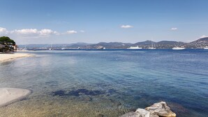 A coastal scene with clear waters, boats, and a distant mountain range. - La Bastide du Port (Saint-Tropez)