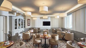 A hotel dining area with round tables, chairs, and pendant lighting. - La Bastide du Port (Saint-Tropez)