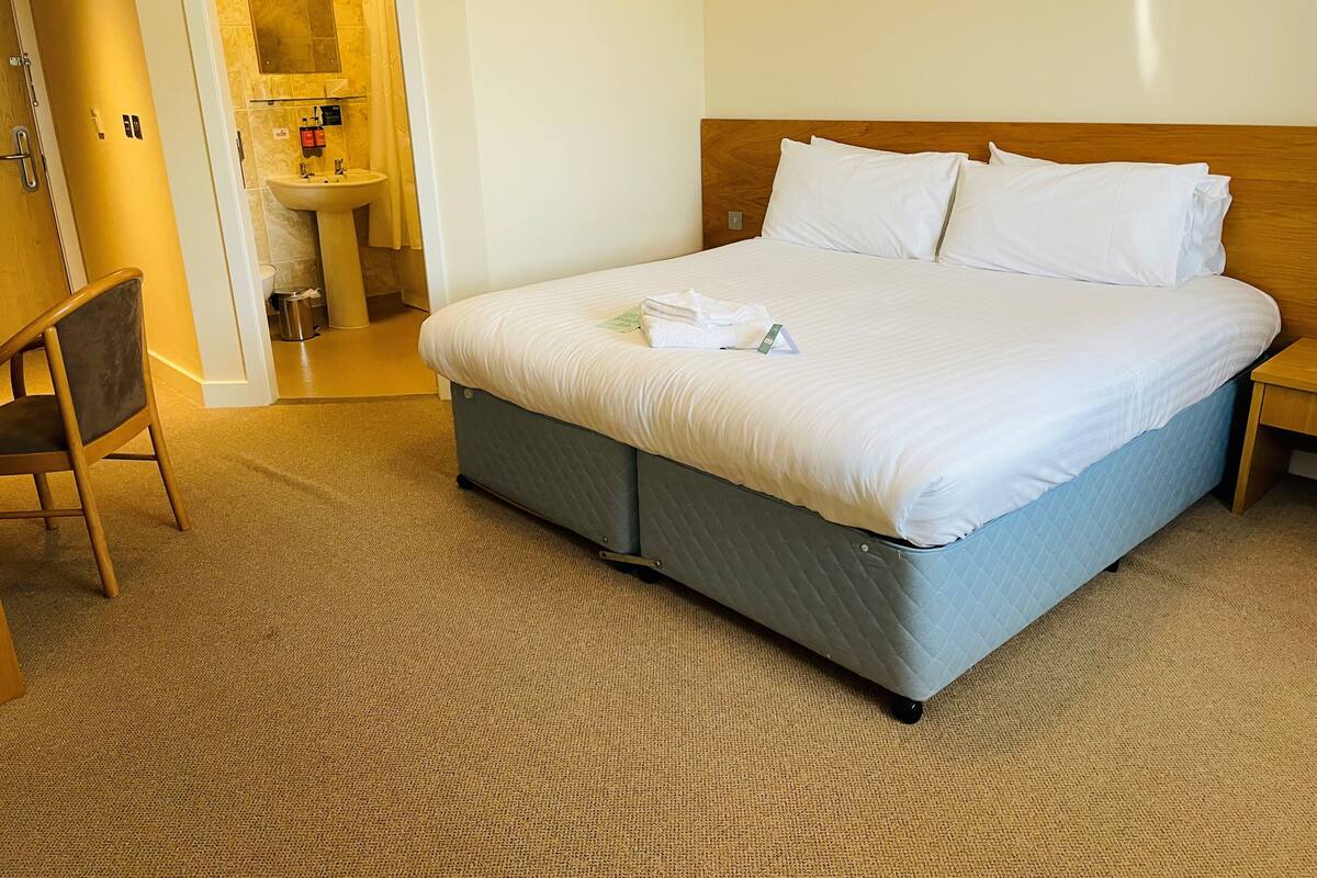 Hotellihuone, jossa on sänky, tuoli, pesuallas ja peili.
