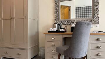 A room with a large wardrobe, a vanity with a mirror, and a desk with a chair.