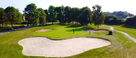 Un campo de golf con búnkeres de arena, un putting green y un sendero para golfistas.
