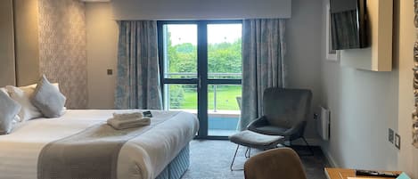 Una habitación de hotel con una cama, una silla, un escritorio y un televisor.