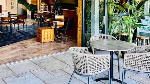 An outdoor patio area with a covered seating area, tables, and chairs.