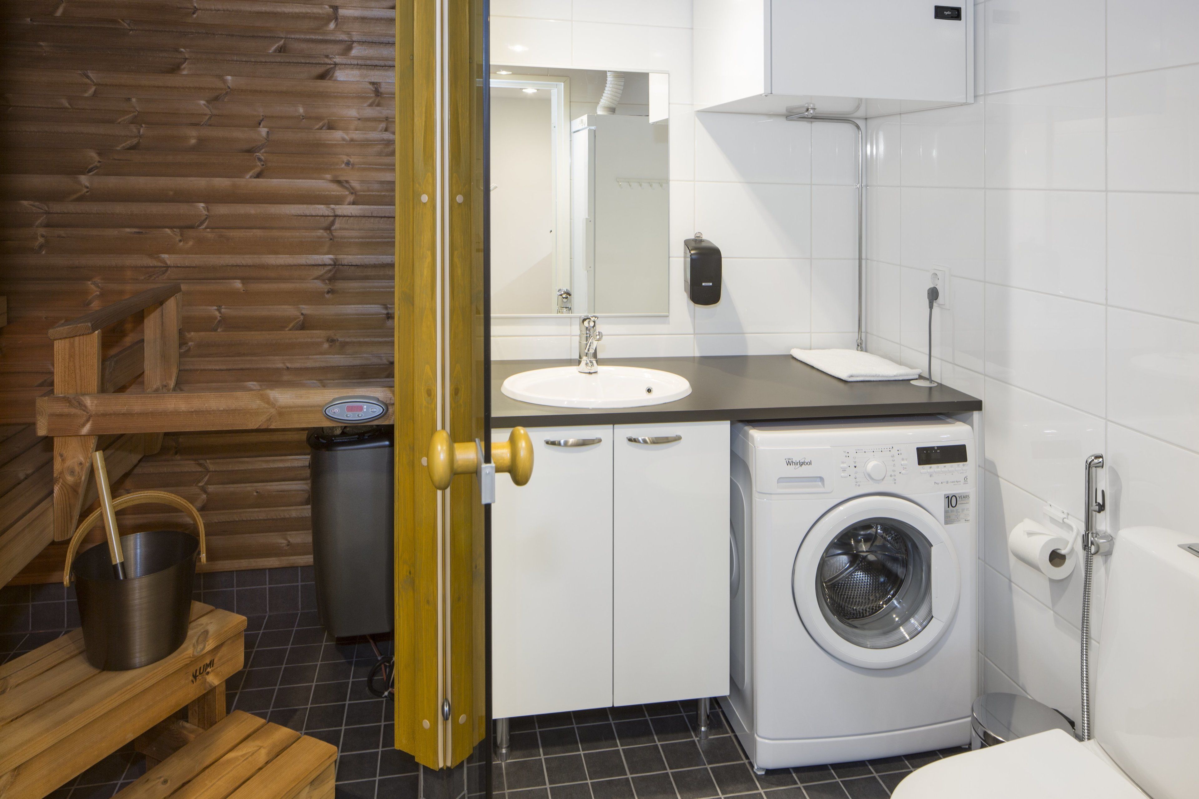 Un bagno moderno con parete in legno, lavandino, lavatrice e water.