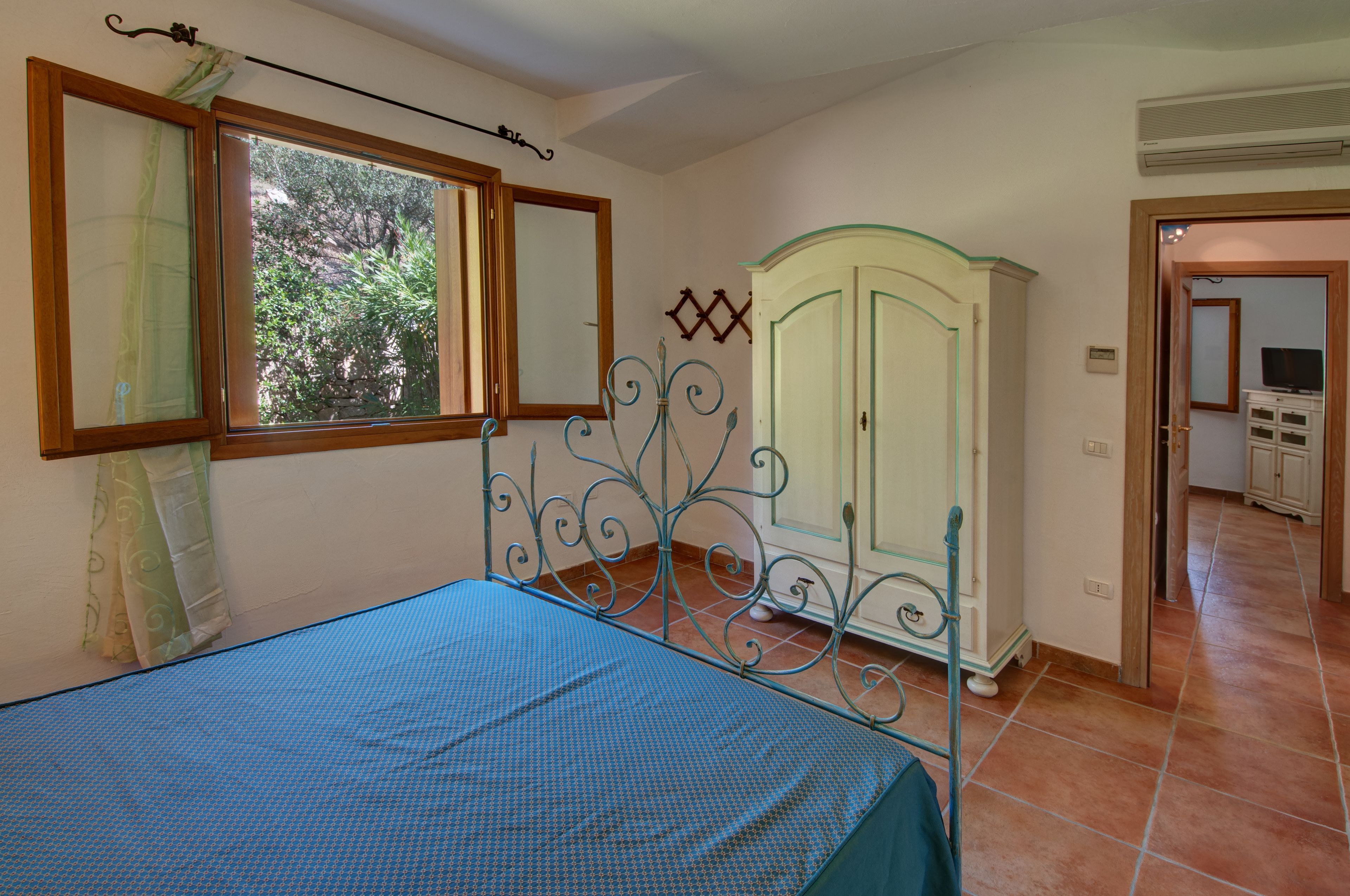 Ein Schlafzimmer mit Bett, Kleiderschrank und einem Fenster mit Vorhängen.