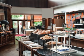 A buffet area with various food items, including breads and cheeses, in a modern setting with wooden furniture and glass display cases.