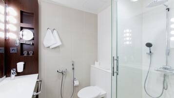 A modern bathroom with a glass-enclosed shower, a white toilet, and a vanity with a mirror and towel rack.
