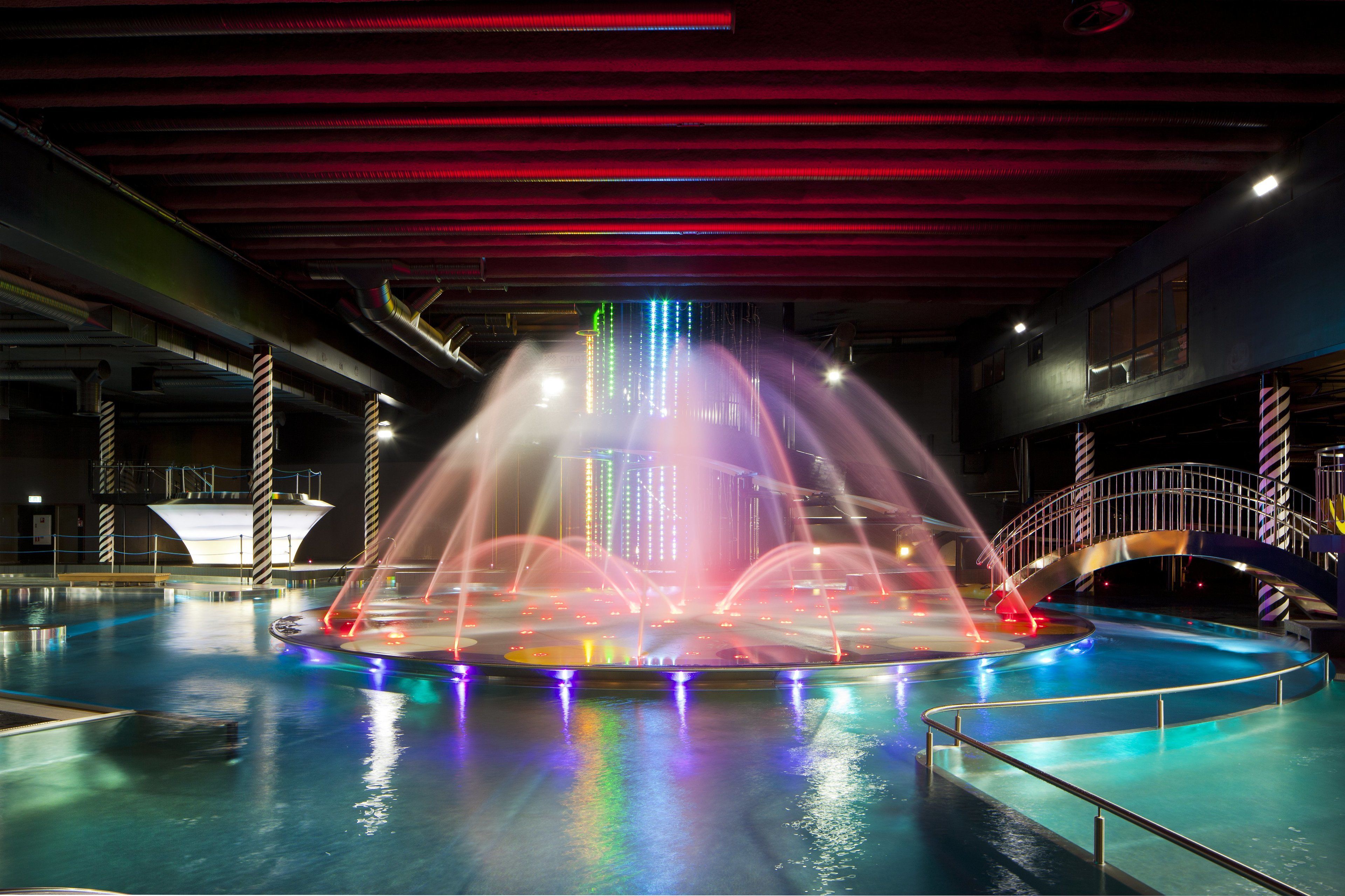 A water fountain with colorful lights and a pool area.