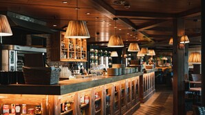 A bar area with wooden cabinets, shelves with bottles, and hanging lamps. - Holiday Club Saimaan Rauha (Lappeenranta)