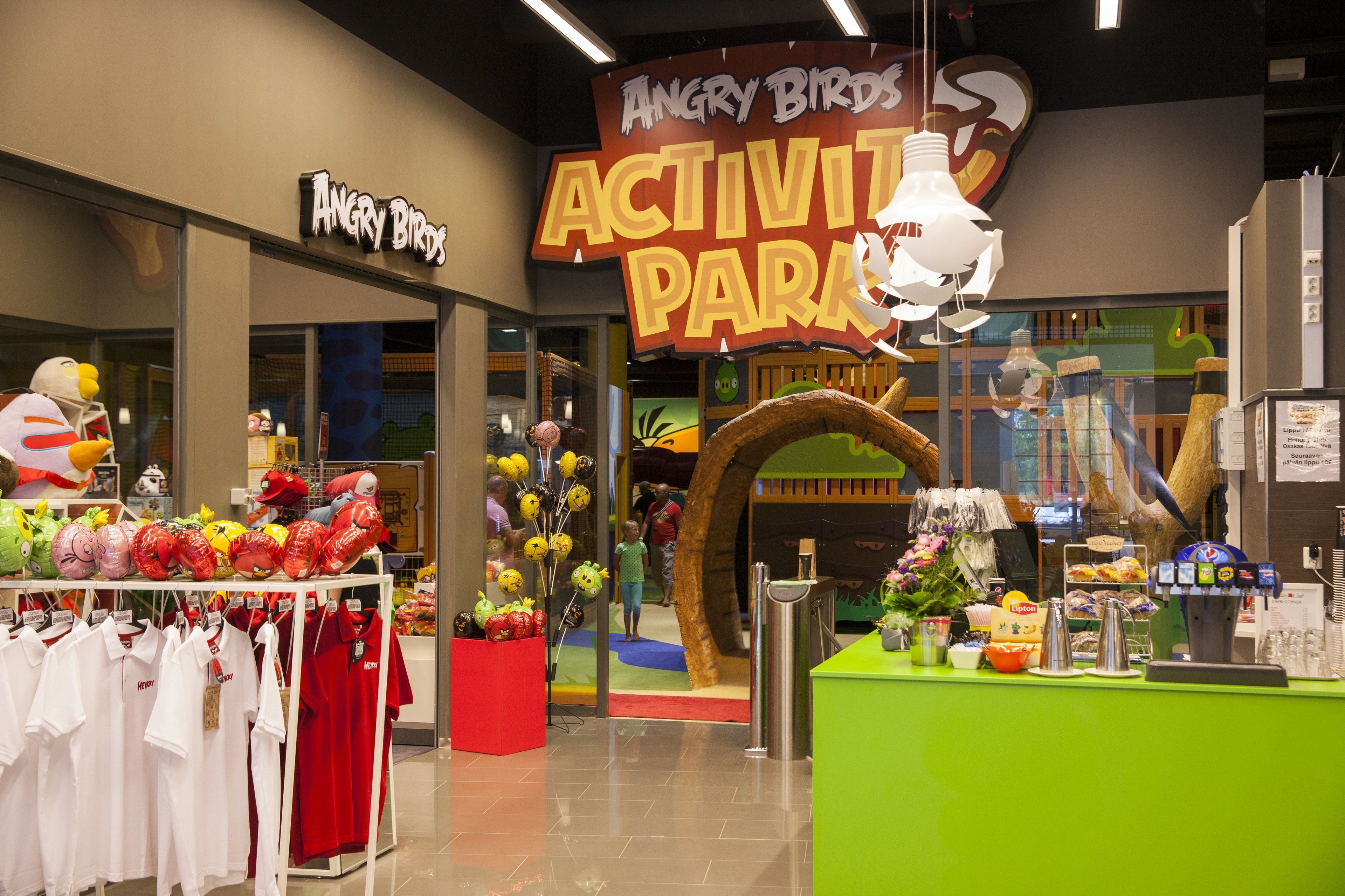Centro de actividades interior con un letrero de 'Angry Birds', una zona de juegos y un mostrador con aperitivos y bebidas.