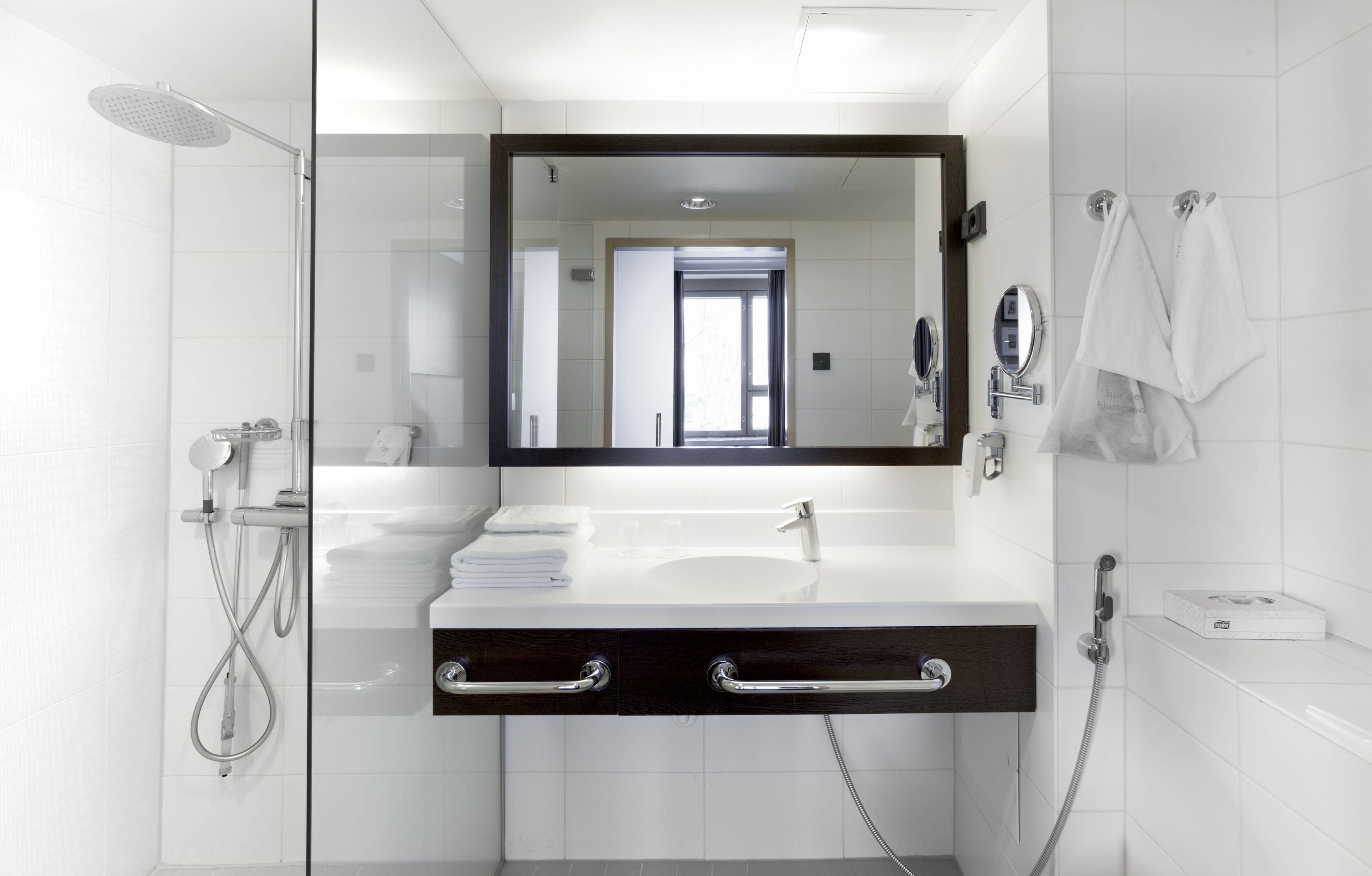A modern bathroom with a glass shower enclosure, a white sink, and a large mirror.