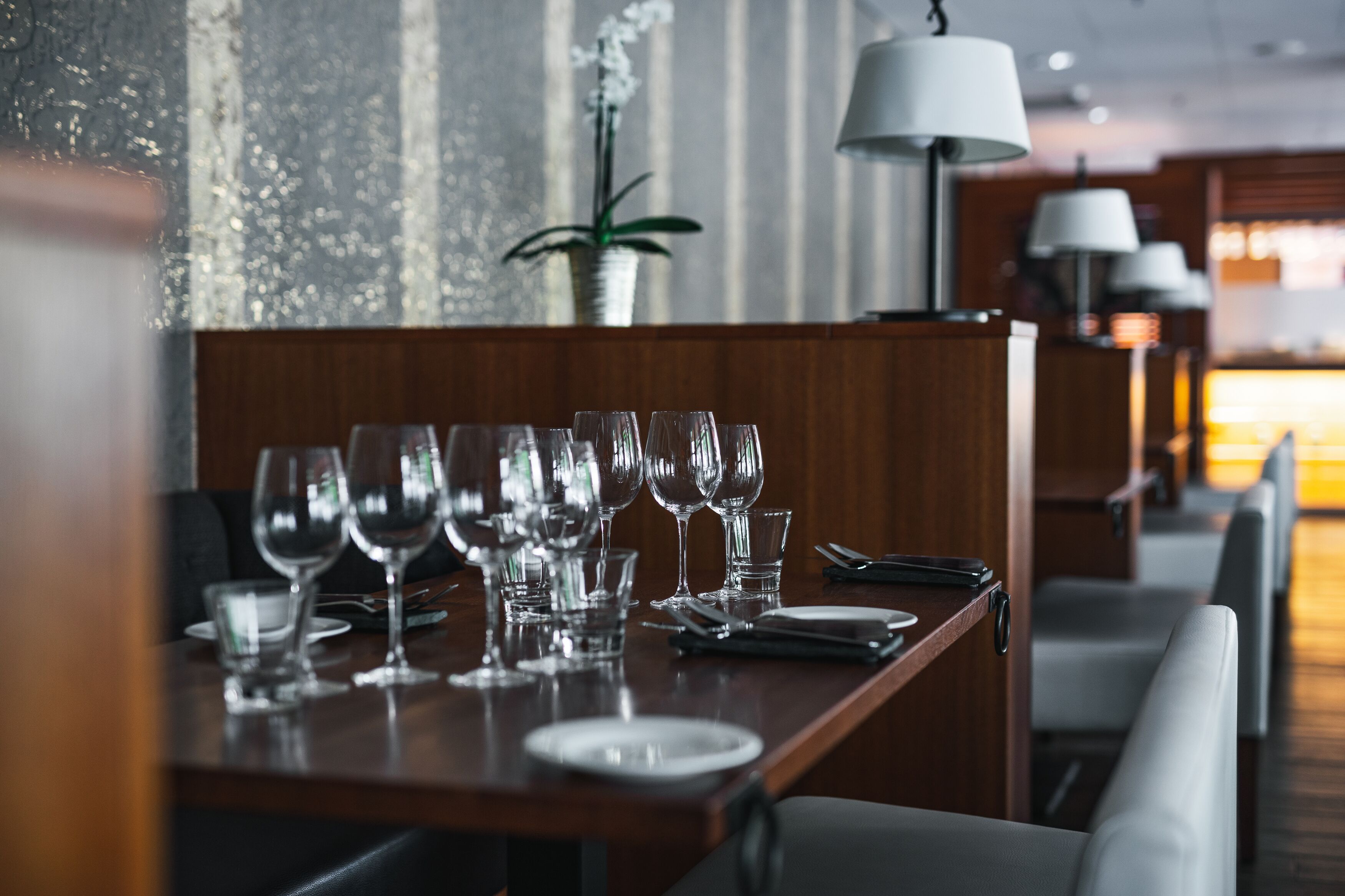 A restaurant setting with a table set for dining, featuring multiple wine glasses and plates.