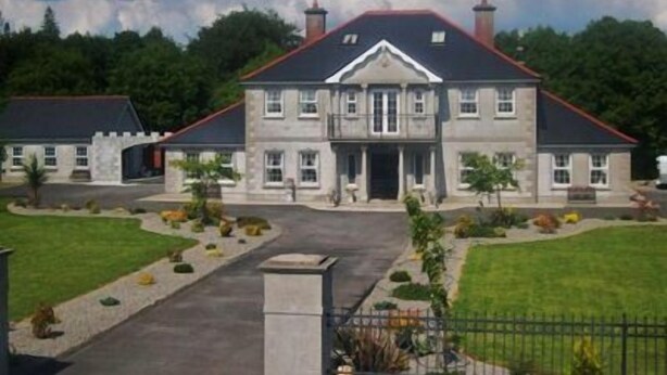 A large, two-story stone building with a symmetrical facade, a central entrance, and a landscaped front yard with a pathway leading to the entrance. - Deerpark Manor Bed & Breakfast (Swinford)