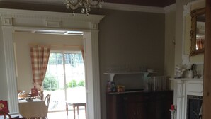 A dining area with a table and chairs, a chandelier, and a view through a window. - Deerpark Manor Bed & Breakfast (Swinford)