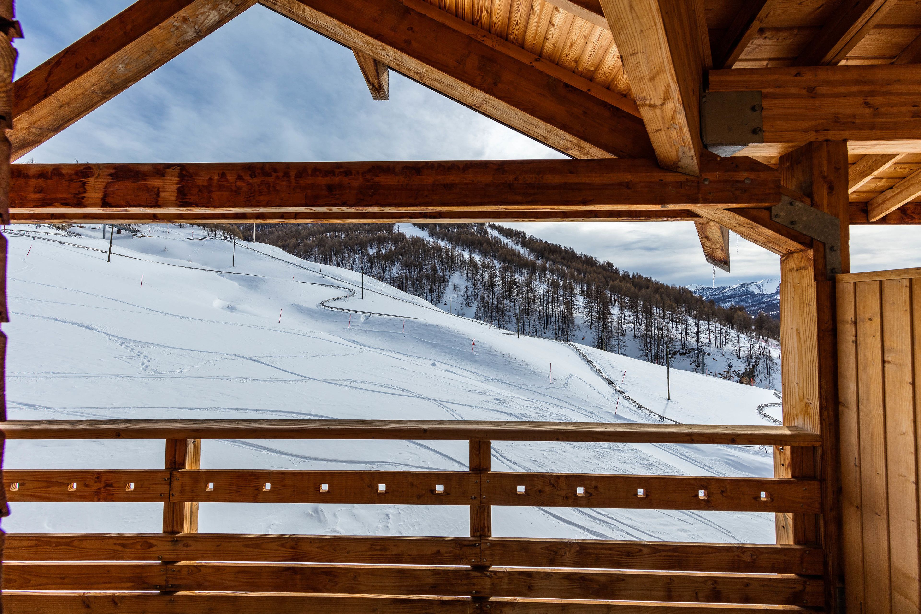 Een houten chalet met uitzicht op een besneeuwde berghelling.