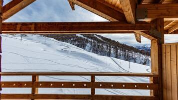 A wooden cabin with a view of a snowy mountain slope.
