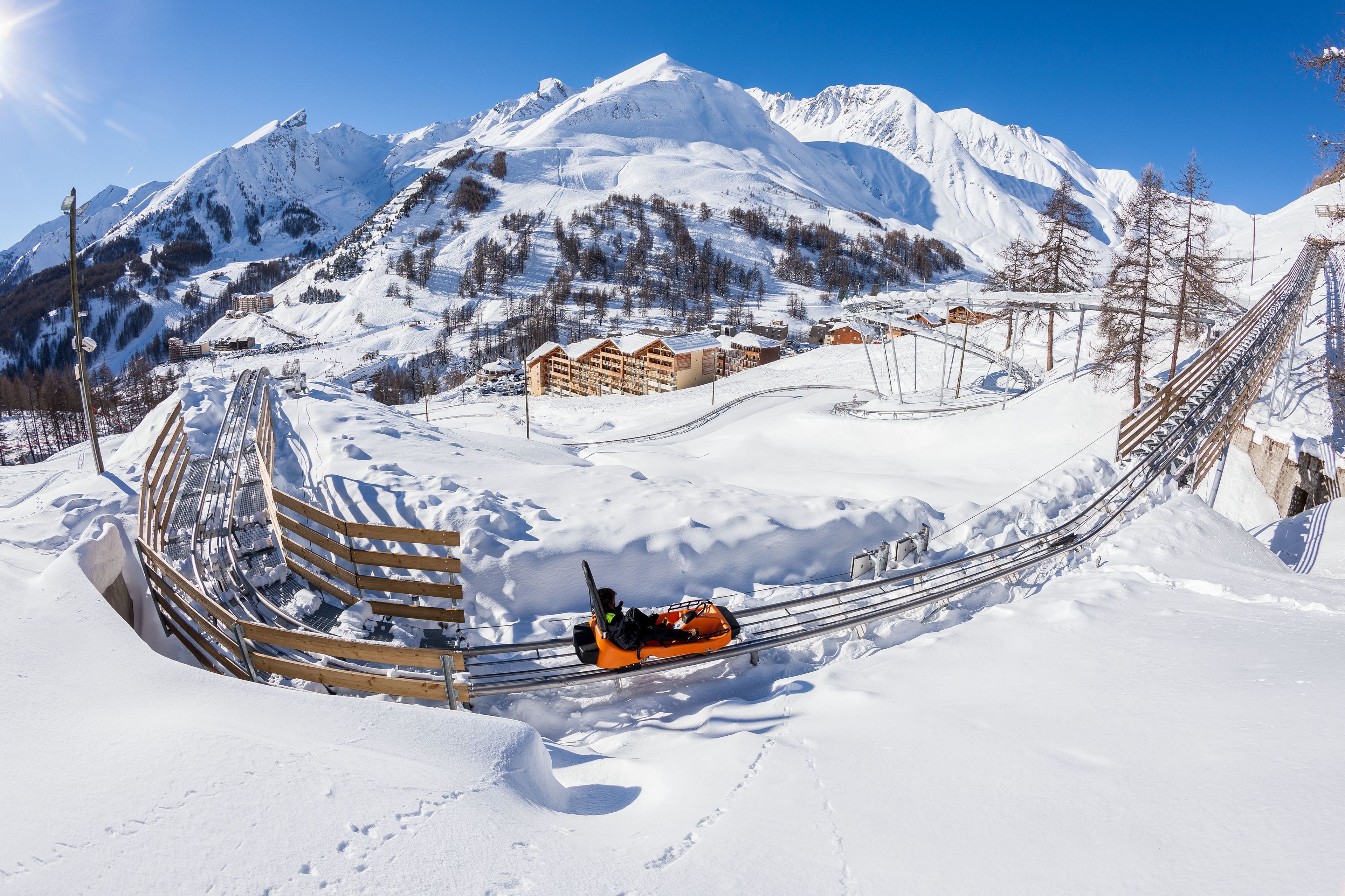 Un paisaje montañoso nevado con un telesilla y edificios al fondo.
