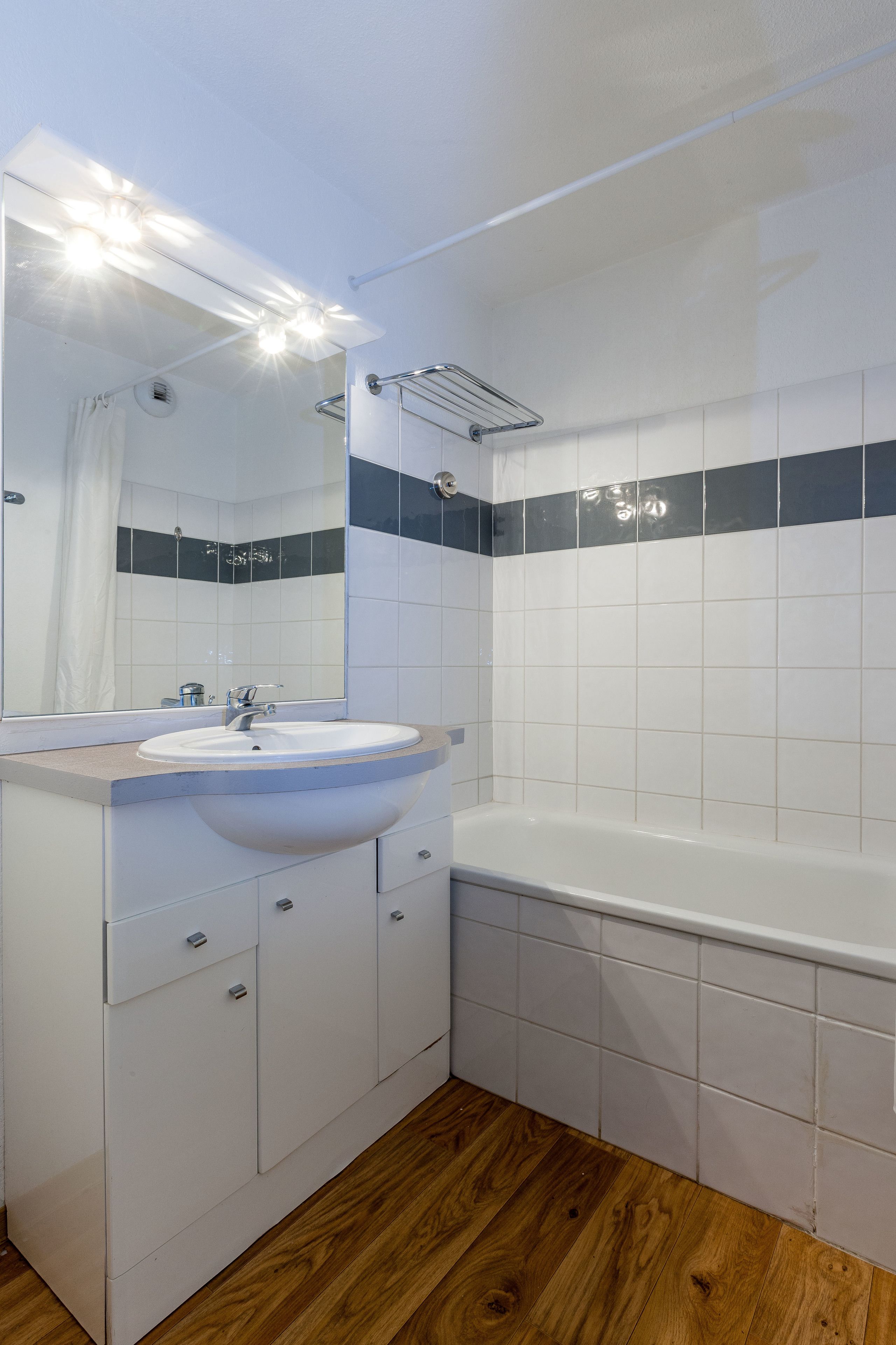 A modern bathroom with a white sink, mirror, and bathtub.
