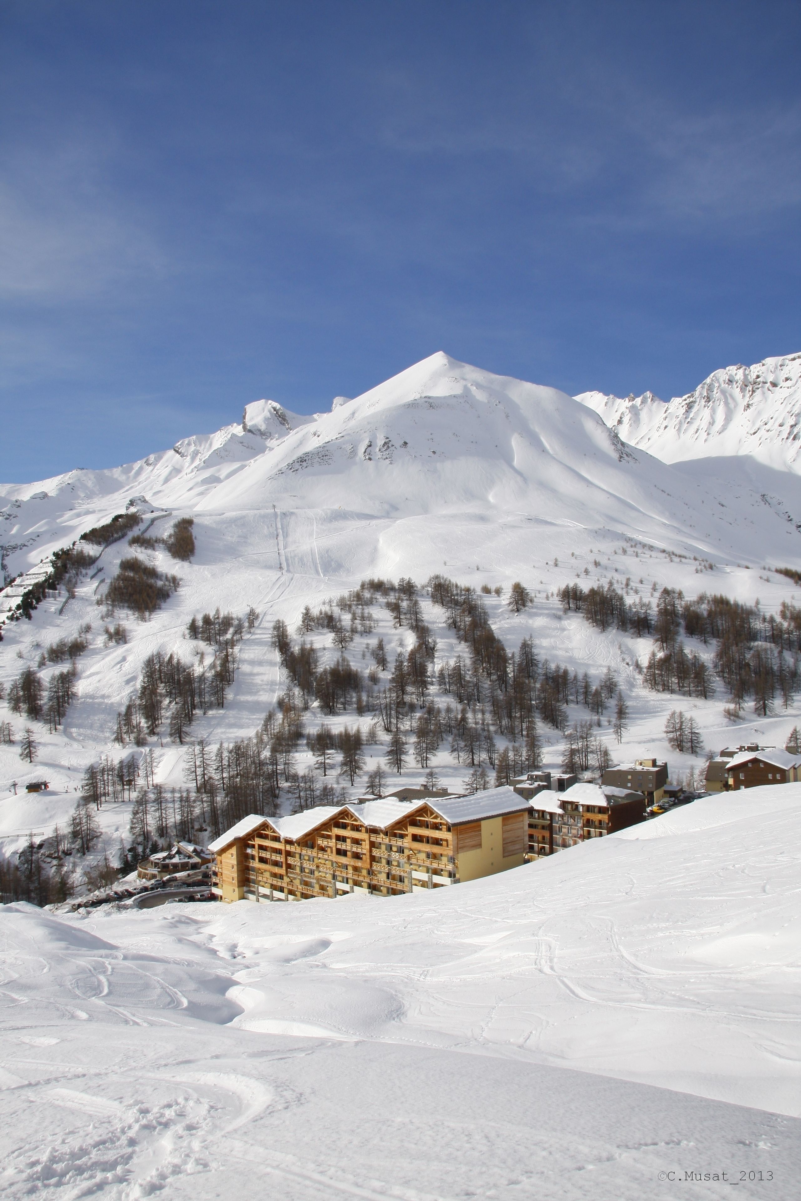 A snow-covered mountain with a ski resort and wooden buildings.