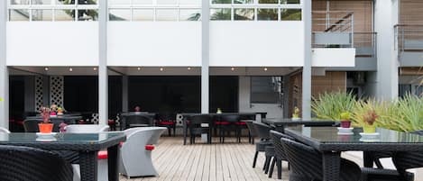 An outdoor patio with wicker furniture and potted plants.