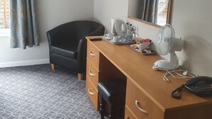A hotel room with a wooden desk, a black leather chair, a flat-screen TV, a large mirror, and a patterned carpet. - The Birley Arms Hotel (Preston)
