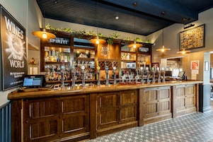 A bar area with a wooden counter, multiple taps, and a menu display.
