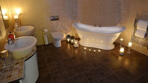 A bathroom with a freestanding bathtub, two sinks, a toilet, and a towel rack. - The Birley Arms Hotel (Preston)